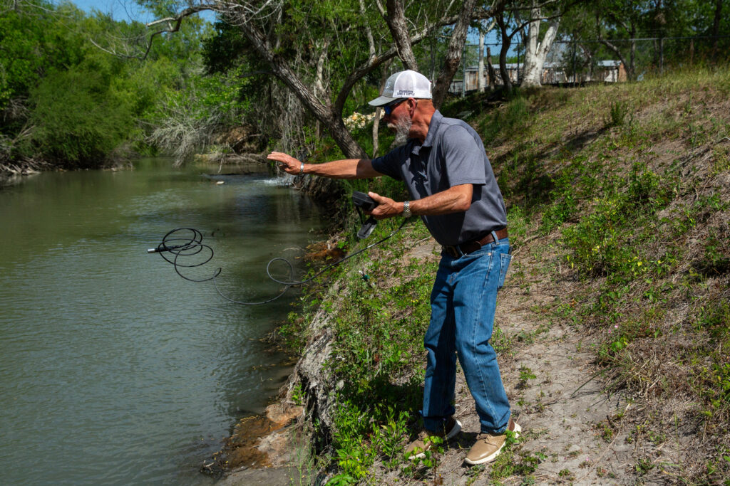 Chris Cuellar uses a conductivity meter to measure salinity in the Nueces River and the city of Corpus Christi’s wells that flow into it. Credit: Dylan Baddour/Inside Climate News