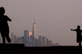 Children play in a park as the skyline of New York City is shrouded by a hazy sky on July 18, 2023. Credit: Gary Hershorn/Getty Images