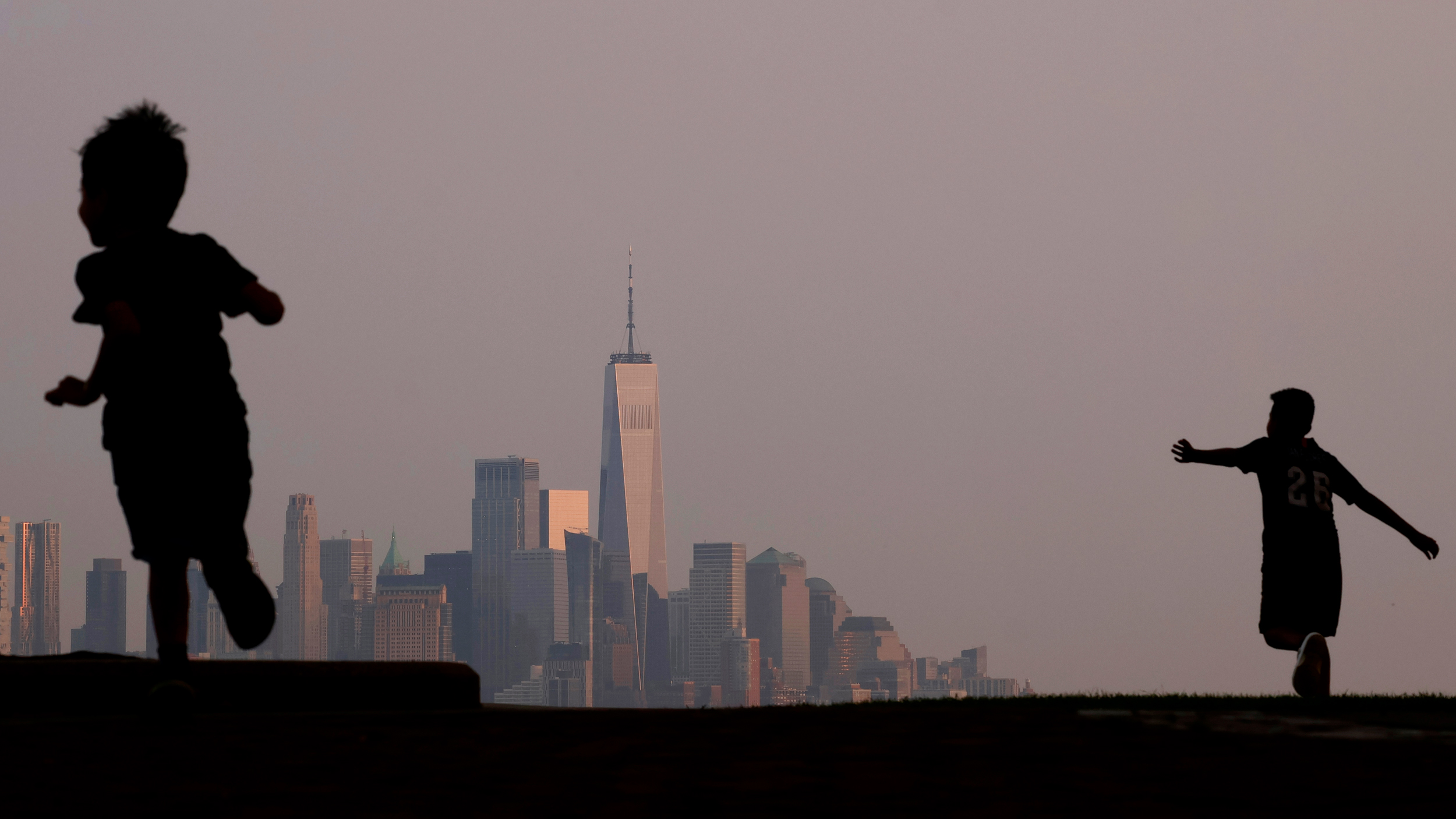Children play in a park as the skyline of New York City is shrouded by a hazy sky on July 18, 2023. Credit: Gary Hershorn/Getty Images