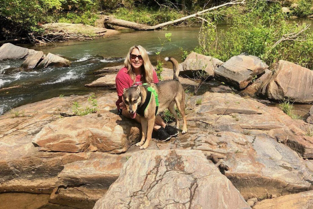 Kim Hicks sits with her dog along Kendall Creek, a place she says has long been part of daily life—and one she worries could change under the proposed Project Ruby data center. Credit: Courtesy of Kim Hicks
