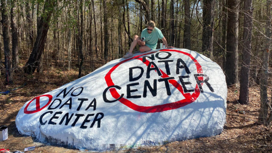 Kim Hicks paints a message opposing a proposed data center onto a neighborhood rock near the Project Ruby site in Muscogee County, Ga., part of a growing grassroots effort against the development. Credit: Courtesy of Kim Hicks