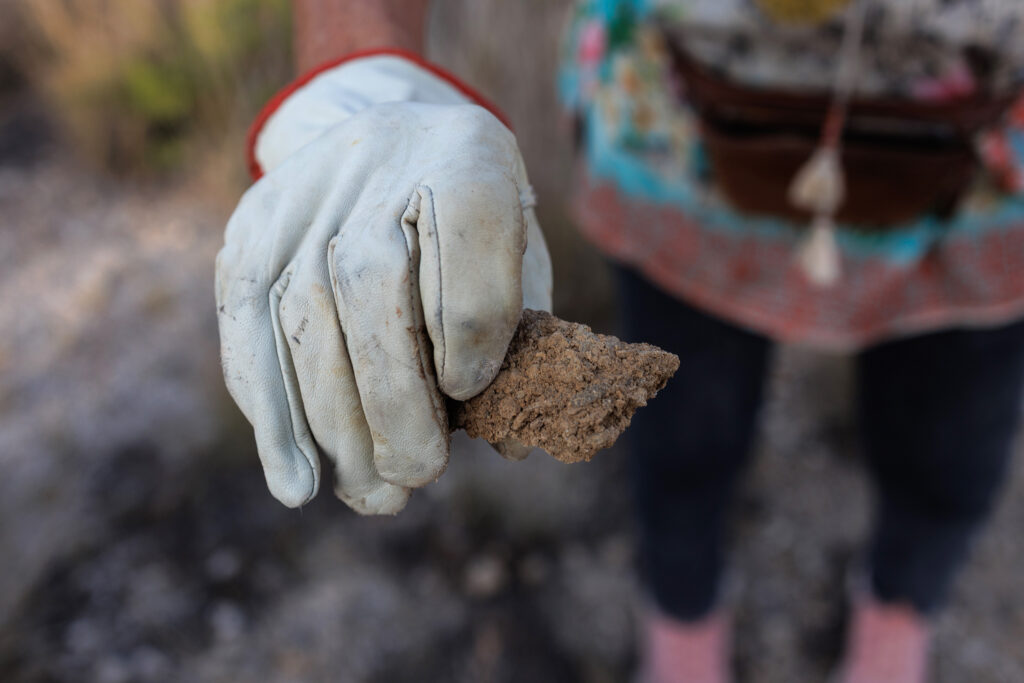 Jackie Chesnutt holds a piece of soil hardened from the produced water of an oil well, which she found next to a well on her property.