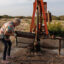 Jackie Chesnutt props up a sign next to a leaking oil well operated by CORE Petro on her property near Knickerbocker, Texas, on Nov. 18, 2025.