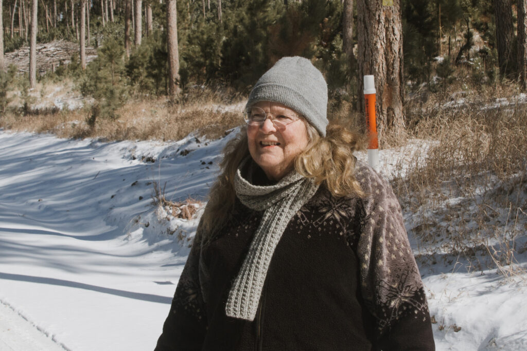 Meg King walks along a snow-covered forest road in the Black Hills of South Dakota, retracing her steps to locate a lithium exploration site. Credit: Carla Samon Ros/CJI