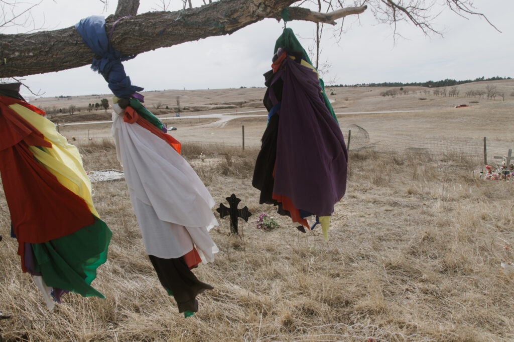 Graves mark the site of the 1890 Wounded Knee Massacre on the Pine Ridge Reservation. Trina Lone Hill, who has ancestors who were killed here, recalls driving by the cemetery with her 10-year-old son after he kept asking why the killings happened. “They wanted our land,” she told him. “It was politics.” Credit: Carla Samon Ros/CJI