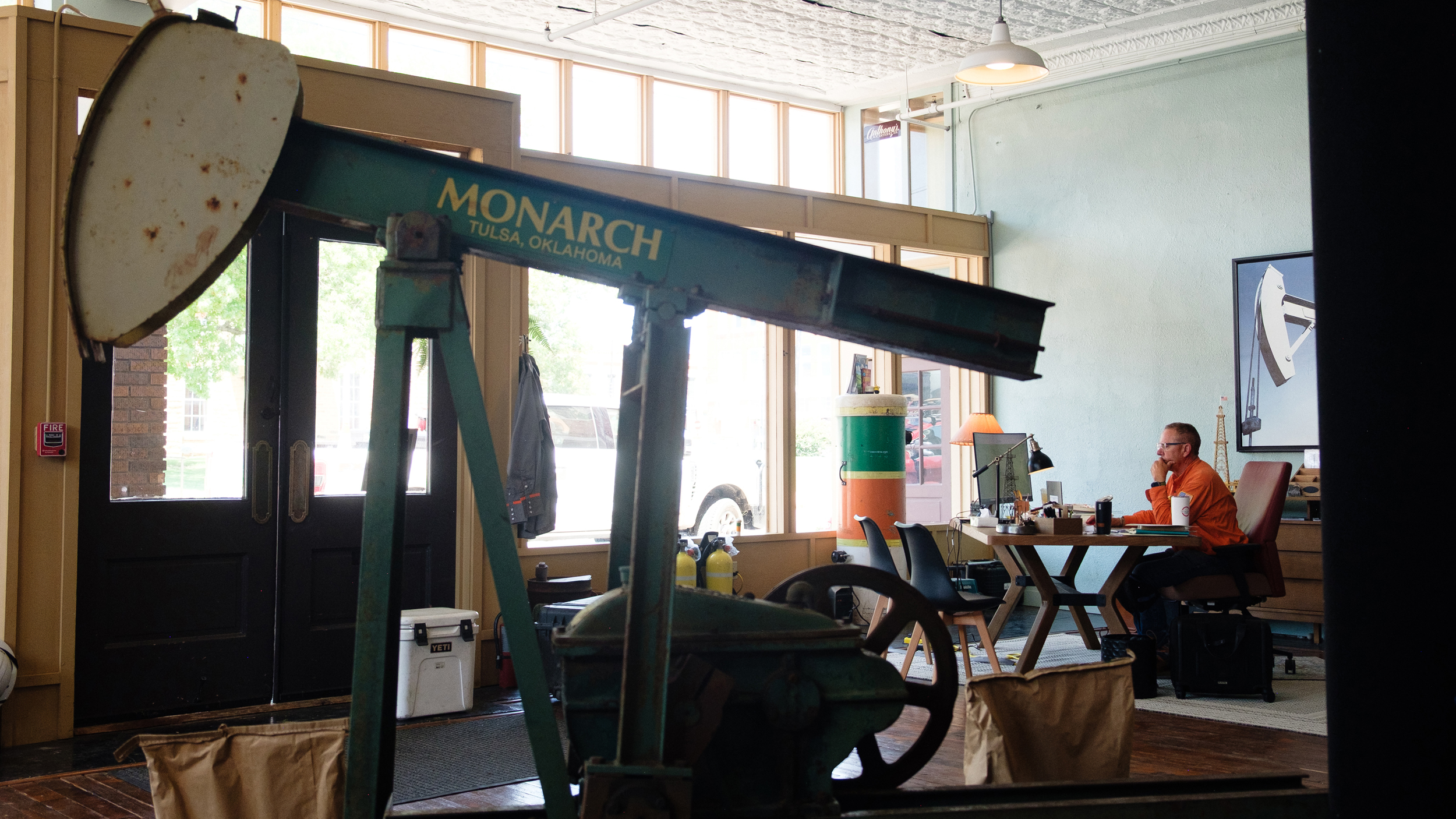 Curtis Shuck works at his desk in Well Done’s Okmulgee office. The pump jack in the office’s entry was removed from a well plugged in the Deep Fork National Wildlife Refuge.
