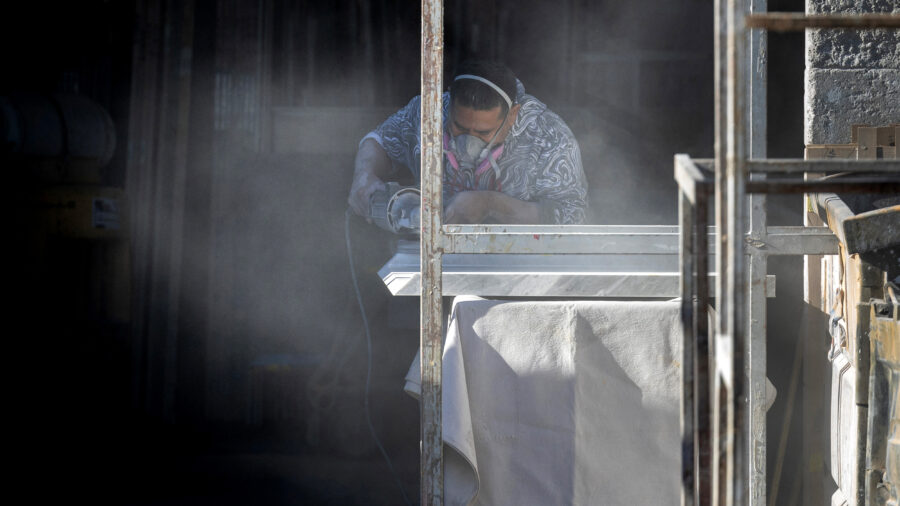 A stone countertop fabricator creates a cloud of dust while wearing a mask to help protect against airborne particles, which can contribute to silicosis, at a shop in Sun Valley, Calif. Credit: Brian van der Brug/Los Angeles Times via Getty Images