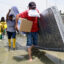 People carry their belongings as they evacuate due to flooding in Yaguachi, Ecuador, on Feb. 25, 2025. Credit: Marcos Pin/AFP via Getty Images