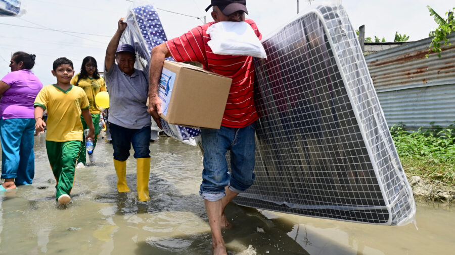 People carry their belongings as they evacuate due to flooding in Yaguachi, Ecuador, on Feb. 25, 2025. Credit: Marcos Pin/AFP via Getty Images