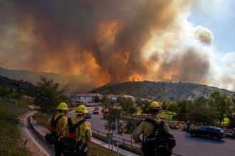 Firefighters monitor the Sandy Fire as it burns close to a residential area on Monday in Simi Valley, Calif. Credit: Apu Gomes/AFP via Getty Images