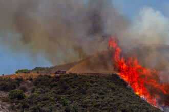 Firefighters work to combat a hotspot in the hills while the Sandy Fire continues to burn near a residential area on Wednesday in Simi Valley, Calif. Credit: Apu Gomes/AFP via Getty Images