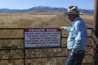 Fifth-generation Montanan Brad Wilson stands beside a dirt road that leads to a century-old public trail that was abandoned by the U.S. Forest Service as part of a controversial land swap with the Yellowstone Club—an exclusive mountaintop retreat for the megarich. Credit: Evan Simon/Floodlight