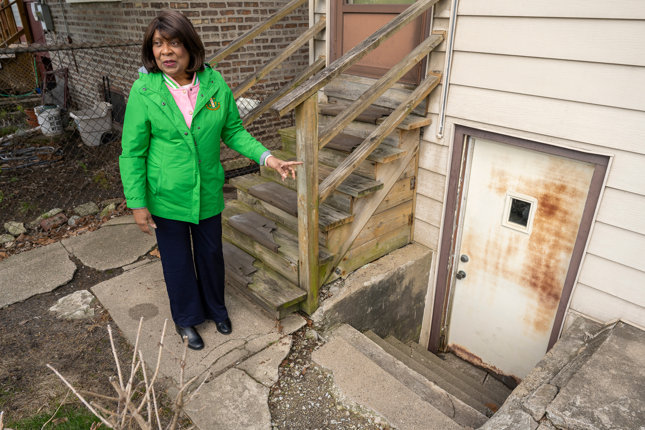 Cheryl Watson explains how nearly three feet of water pools by her basement door, which then seeps into her basement, in her backyard during heavy rains. Credit: Tyler Pasciak LaRiviere/Sun-Times