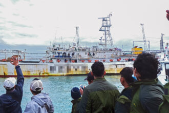 Fishers wave from onboard a Chinese-flagged squid jigger. Credit: Environmental Justice Foundation