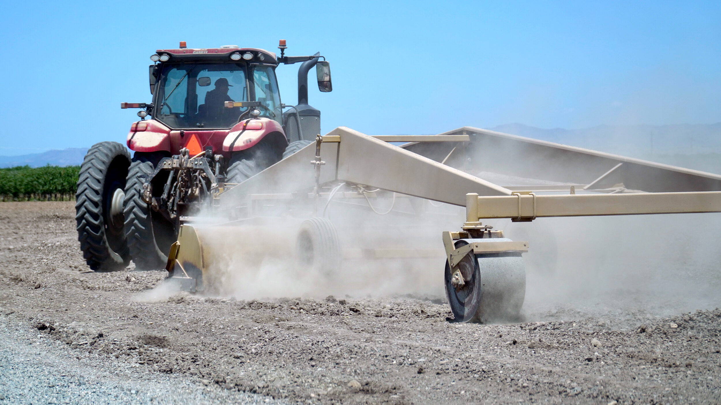 A worker operates a tractor near the entrance to Hillcrest Dairy in May. The Le Grand farm has around 8,000 cows. Credit: Steven Rodas/Inside Climate News