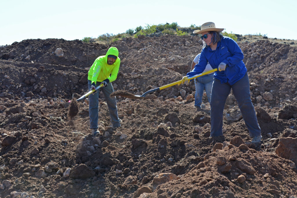 Becca Cozad, the Amphibian and Reptile Conservancy’s Southwest program manager, and Chad Rubke, a wildlife specialist at the Arizona Game and Fish Department, shovel dirt atop an aquatic liner for a pond. Credit: Wyatt Myskow/Inside Climate News