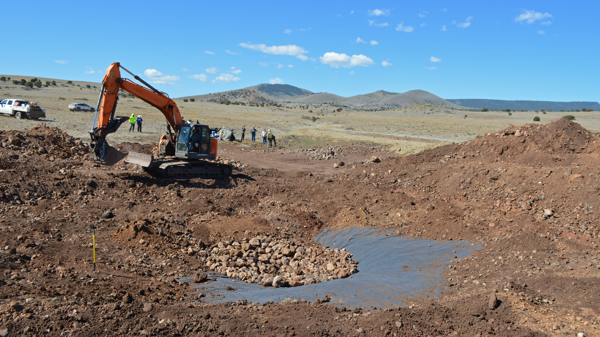 A worker uses an excavator to shovel rocks and dirt at the pond site. Credit: Wyatt Myskow/Inside Climate News