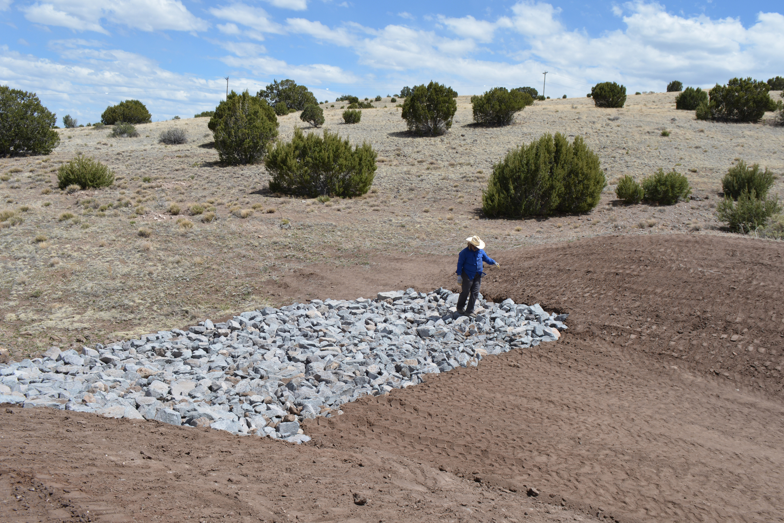 Becca Cozad inspects rocks that will help channel water flow near the site of an artificial pond. Credit: Wyatt Myskow/Inside Climate News