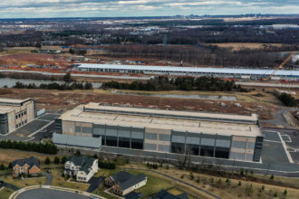 A Microsoft data center is seen under construction behind a recently constructed Amazon data center in Aldie, Va., on Jan. 20, 2023. Credit: Jahi Chikwendiu/The Washington Post via Getty Images