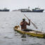 A fisherman paddles in front of commercial fishing boats off the coast of Dakar, Senegal. Credit: John Wessels/AFP via Getty Images