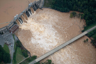 Muddy flood waters of the Catawba River pour over the Oxford Dam, threatening a highway bridge in the aftermath of Hurricane Helene on Sept. 28, 2024, in Hickory, N.C. Credit: Steve Exum/Getty Images
