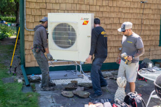 HVAC technicians install a heat pump system at a home in Charlotte, Vt., on July 21, 2025. Credit: Robert Nickelsberg/Getty Images