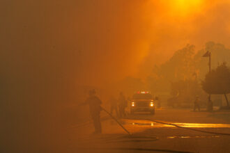 Firefighters are barely visible as smoke from the Bain Fire fills the air on May 19 in Jurupa Valley, Calif. Credit: Gina Ferazzia/Los Angeles Times via Getty Images