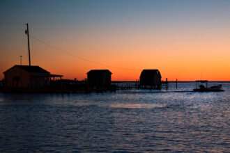 A fisherman passes crab shanties during sunrise Tangier, Va. Credit: Jim Watson/AFP via Getty Images