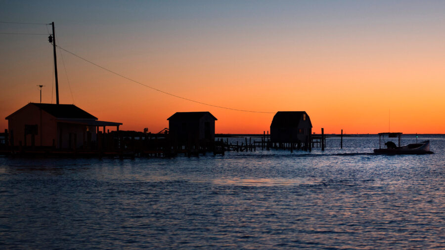 A fisherman passes crab shanties during sunrise Tangier, Va. Credit: Jim Watson/AFP via Getty Images