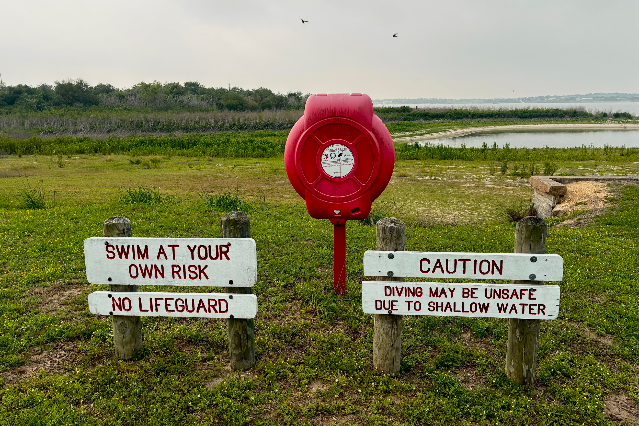 Lake Corpus Christi dropped below 10 percent full in March, the lowest on record since it was first filled in the late 1950s. Signs about swimming sit far from the water’s edge on April 28. Credit: Dylan Baddour/Inside Climate News