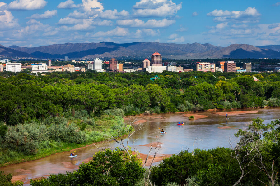 People paddle the Rio Grande with downtown Albuquerque in the background. Credit: City of Albuquerque