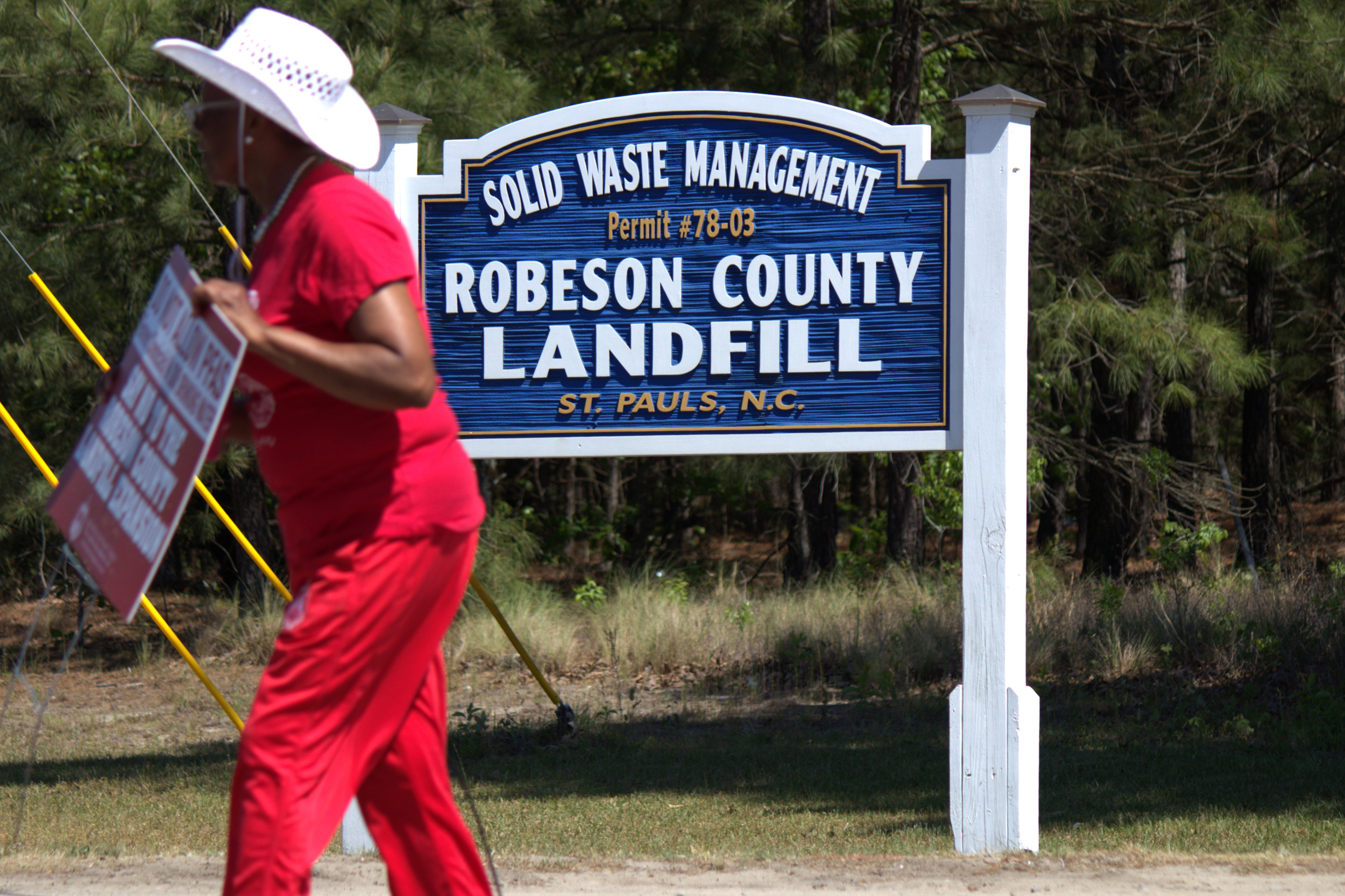 Viv Tolson Wayne walks past the sign welcoming people to the Robeson County Landfill in St. Pauls after blocking its entrance as part of a protest against its expansion on April 18. Credit: Morgan Casey