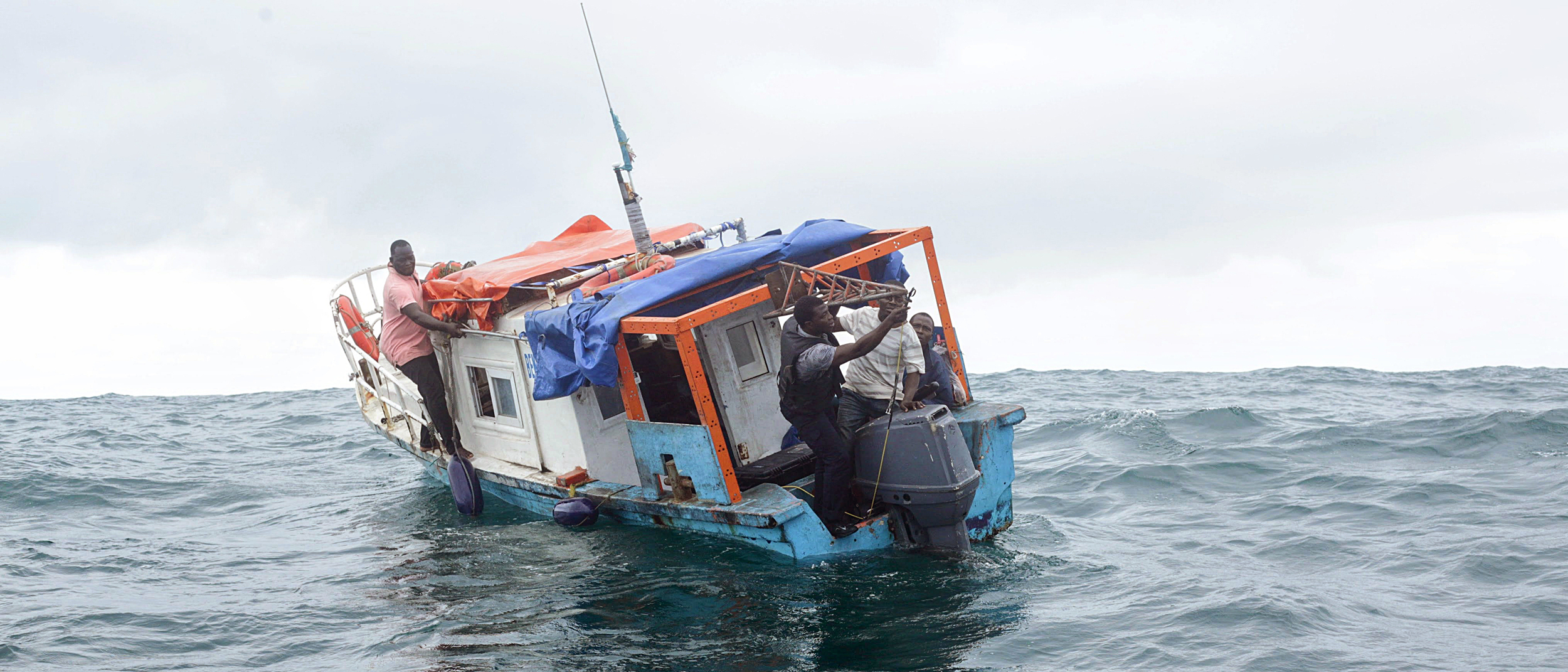 Gérard Zinzindohoué and his team prepare to deploy a sonar scanner from the stern of a local fishing boat. Credit: Ghislain Adjahouisso