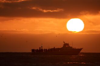 A commercial fishing boat is seen off the coast of San Diego as the sun sets on July 5, 2025. Credit: Kevin Carter/Getty Images