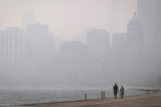 People walk along Lake Michigan as smoke from Canadian wildfires blankets Chicago on Thursday. Credit: Scott Olson/Getty Images