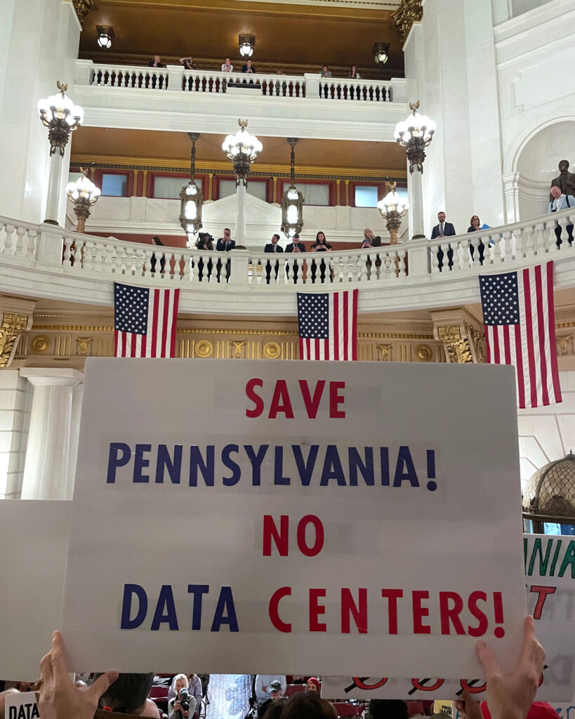 A protester holds up a sign during a data center moratorium rally in the State Capitol rotunda. Credit: Courtesy of Food & Water Watch