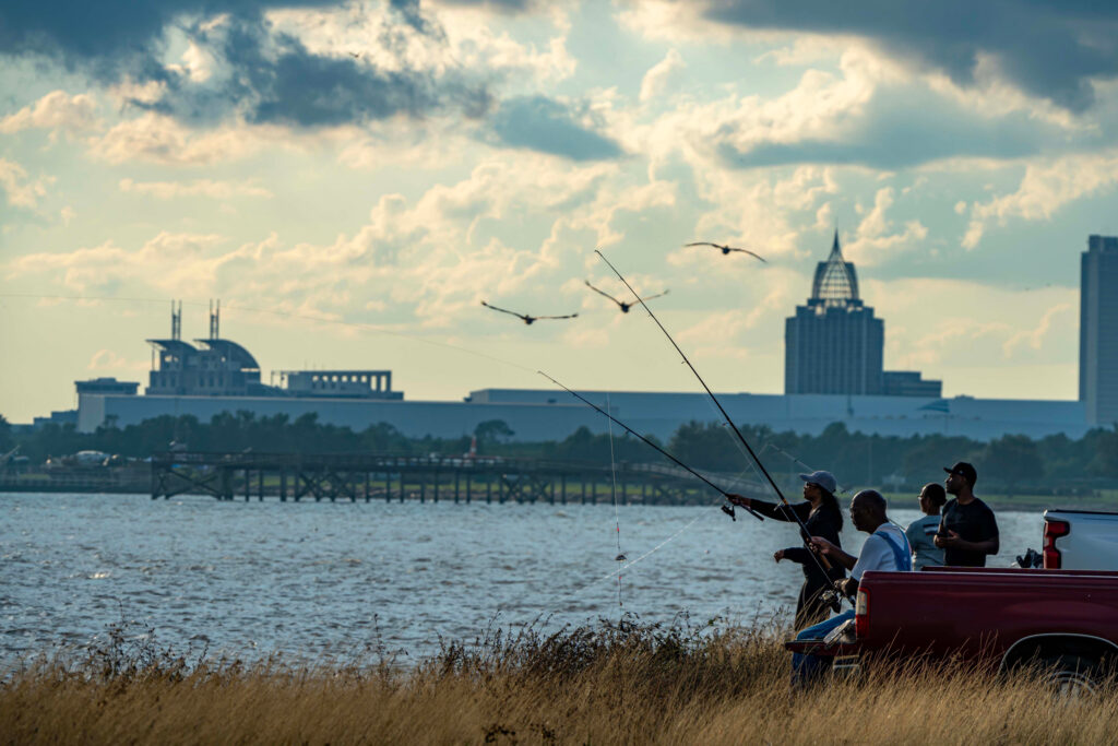 People fish in the Mobile Bay Causeway with the skyline of Mobile, Ala., in the background. Credit: Lee Hedgepeth/Inside Climate News