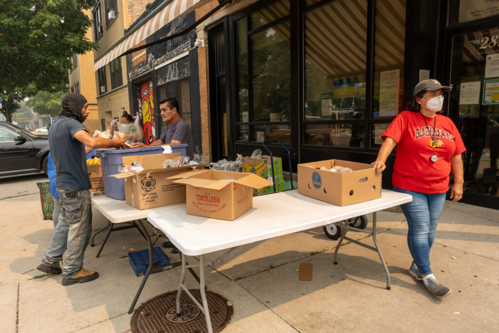 Digna Abrego (right) hands out free groceries at the European American Association in Humboldt Park on Thursday. Credit: Keerti Gopal/Inside Climate News