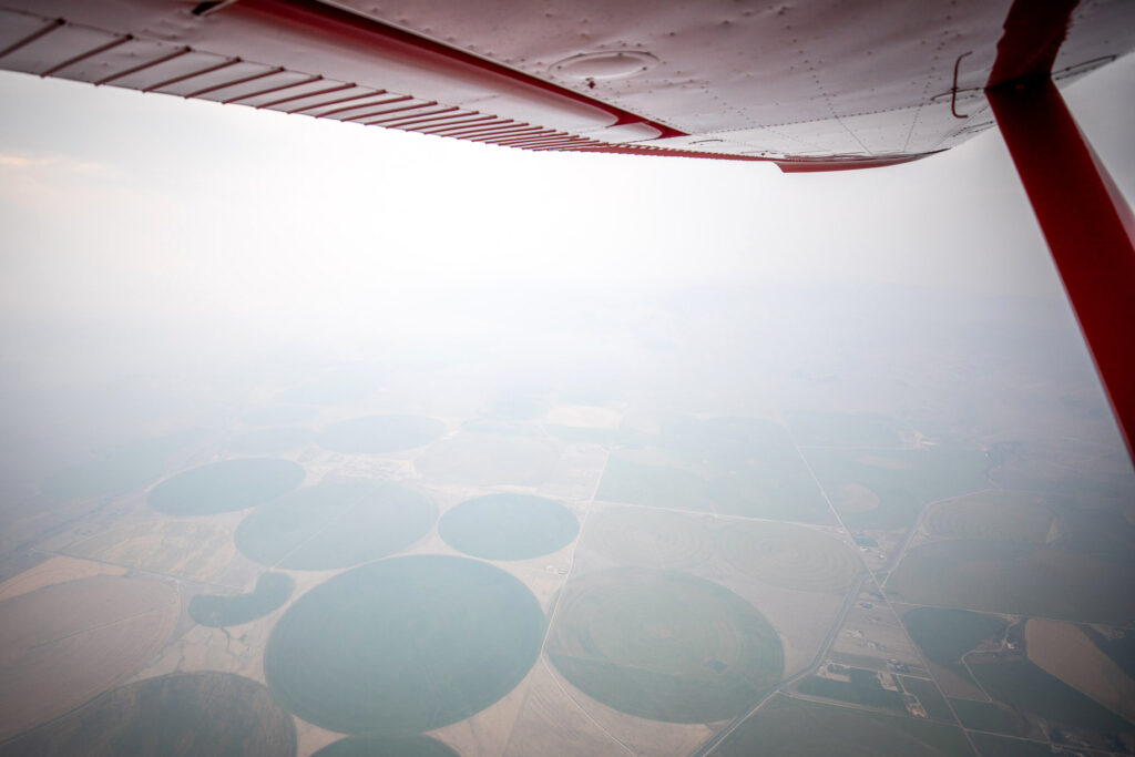 An aerial view northeast of Dillon, Mont., shows agricultural fields surrounded by thick smoke from the Sand Creek Fire on Aug. 13. Credit: Chris Boyer/LightHawk
