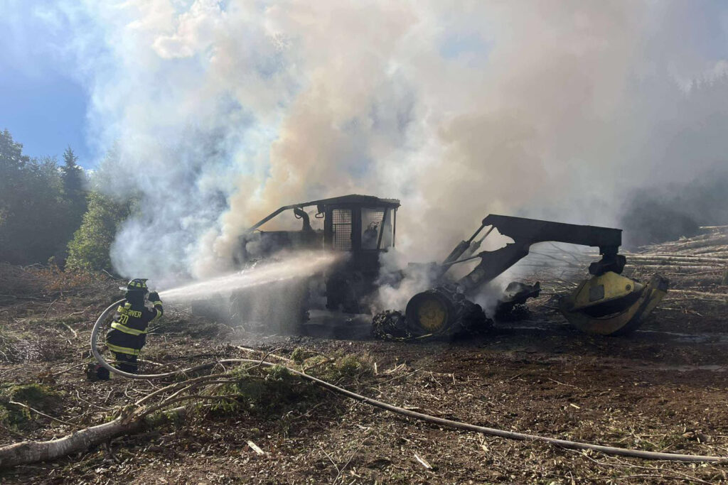 A firefighter puts out a heavy machinery fire in Cathance Township, Maine, in 2025. Most wildfires in the Northeast are sparked by human causes, such as vehicle fires, campfires or debris burns. Credit: Maine Forest Service