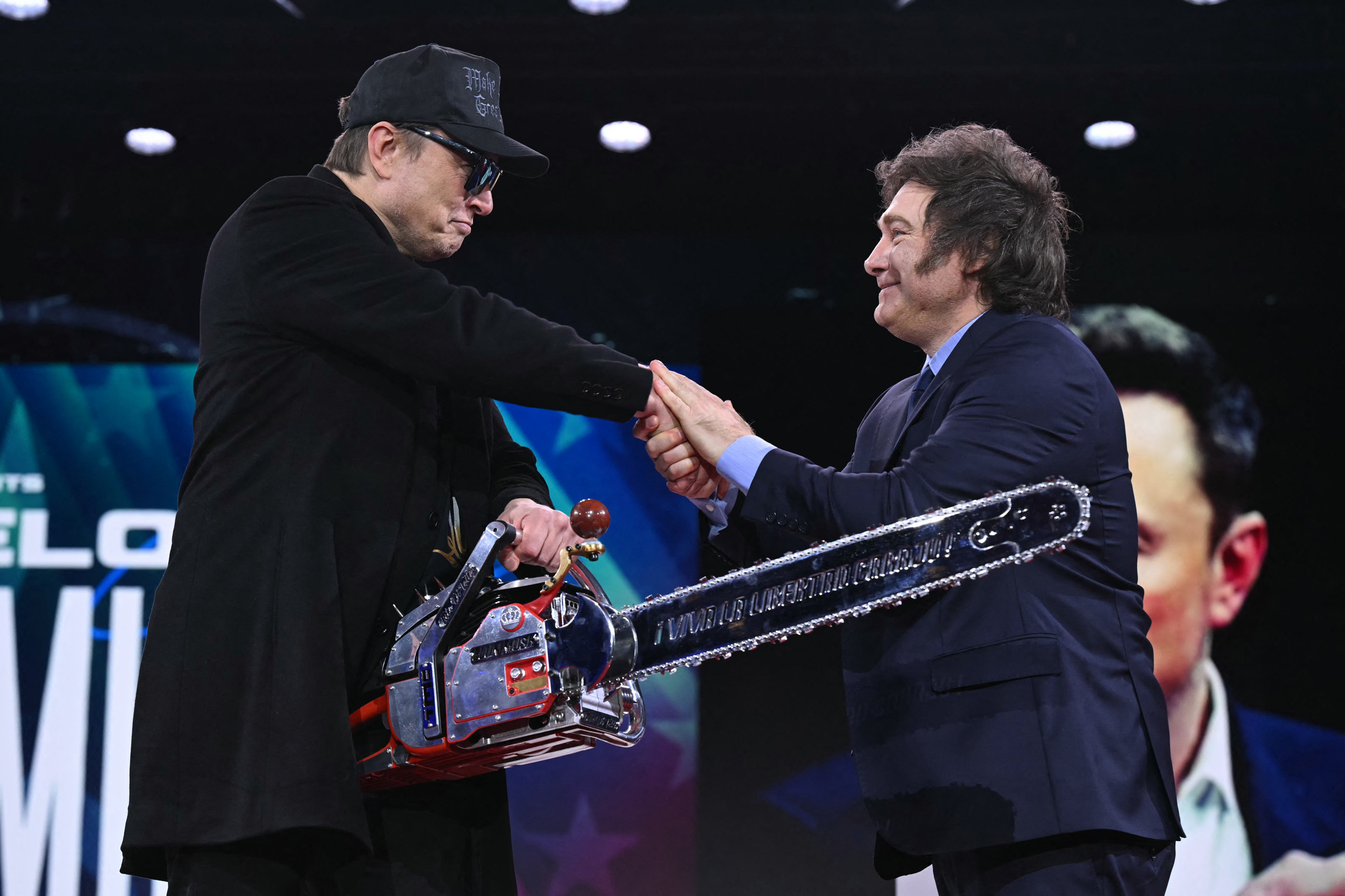 Elon Musk holds a chainsaw as he shakes hands with Argentinian President Javier Milei at the annual Conservative Political Action Conference in Oxon Hill, Md., on Feb. 20, 2025. Credit: Saul Loeb/AFP via Getty Images