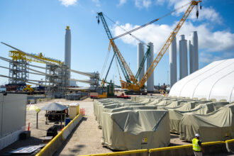 Offshore wind materials sit next to idle construction equipment at the State Pier in New London, Conn., on Aug. 25, 2025. Credit: Tyler Russell/Connecticut Public via Getty Images