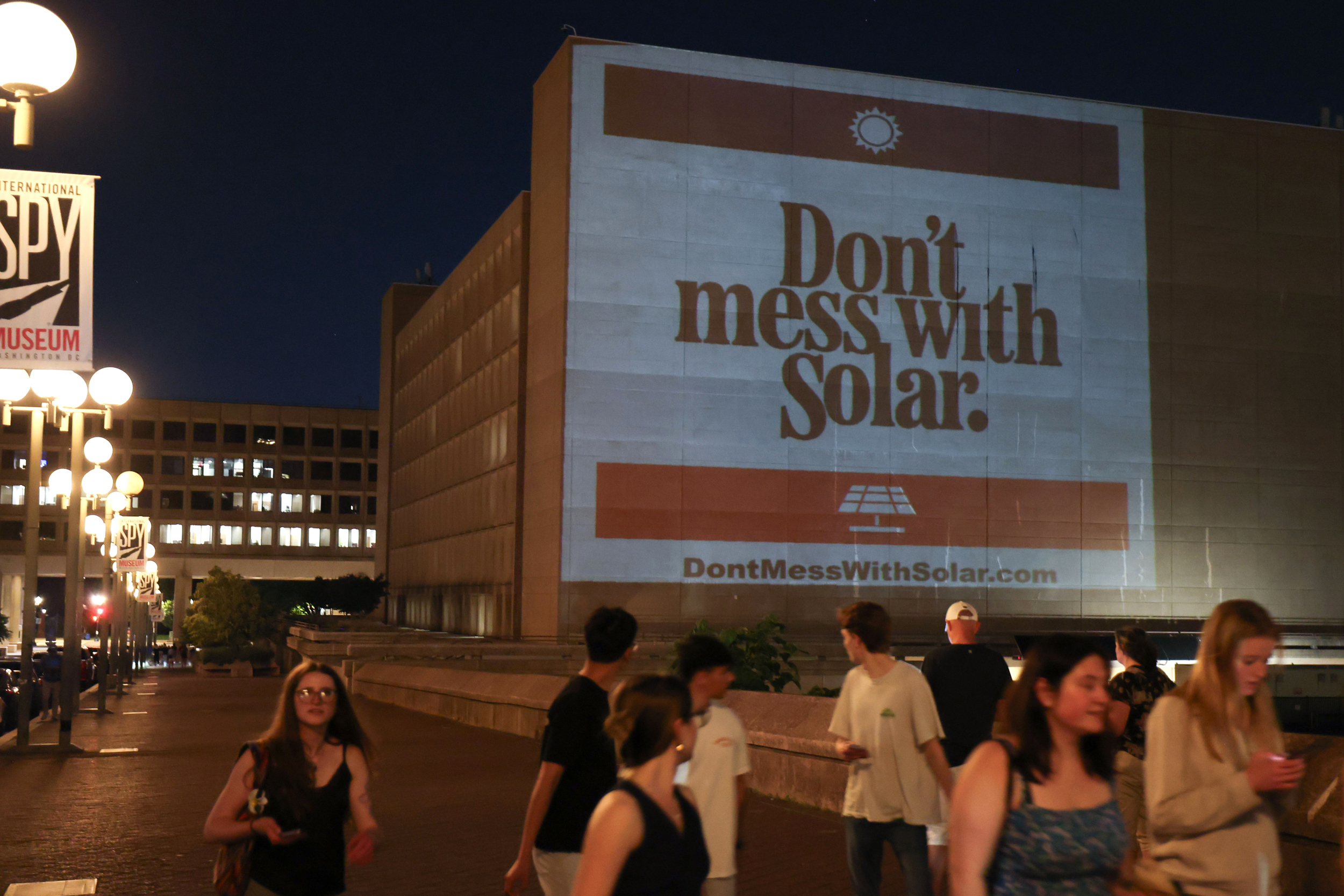 People walk by projections displayed by the Invest in Tomorrow Coalition celebrating Rep. Chip Roy’s loss outside the Department of Energy on May 28 in Washington, D.C. Credit: Tasos Katopodis/Getty Images for Invest in Tomorrow Coalition Action, Inc.