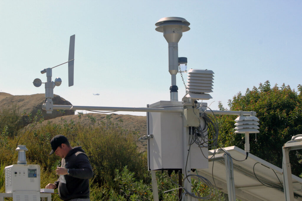 A Department of Energy radiological technician changes out filters in perimeter air monitors near the Santa Susana Field Laboratory on May 22. Credit: Josh Mengers/DOE