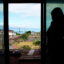 Wildfire survivor Krista Woodward opens the sliding glass door at her stalled home reconstruction on July 1 in Lahaina, Hawaiʻi. Credit: Kevin Fujii/Civil Beat