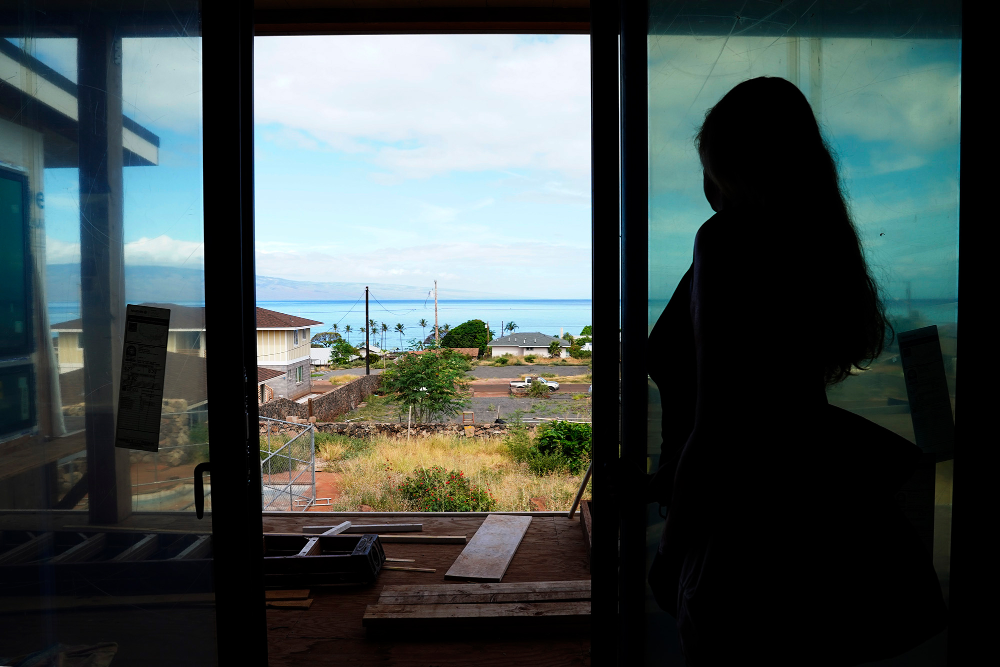 Wildfire survivor Krista Woodward opens the sliding glass door at her stalled home reconstruction on July 1 in Lahaina. Credit: Kevin Fujii/Civil Beat