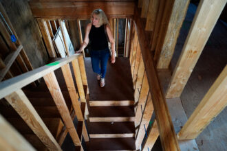 Krista Woodward walks through her stalled home reconstruction on July 1 in Lahaina. Credit: Kevin Fujii/Civil Beat
