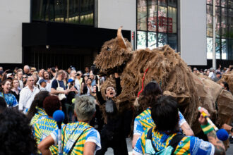 Puppeteers and their buffalo encounter a marching band near City Hall in downtown Manhattan on Saturday. Credit: Jake Bolster/Inside Climate News