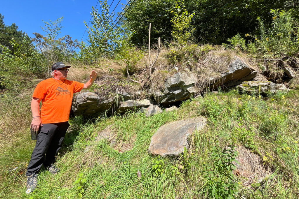 Bobby Hughes gestures toward an old mine shaft where an opening allows cold, toxic air to emerge. Credit: Jessica Klein/Inside Climate News