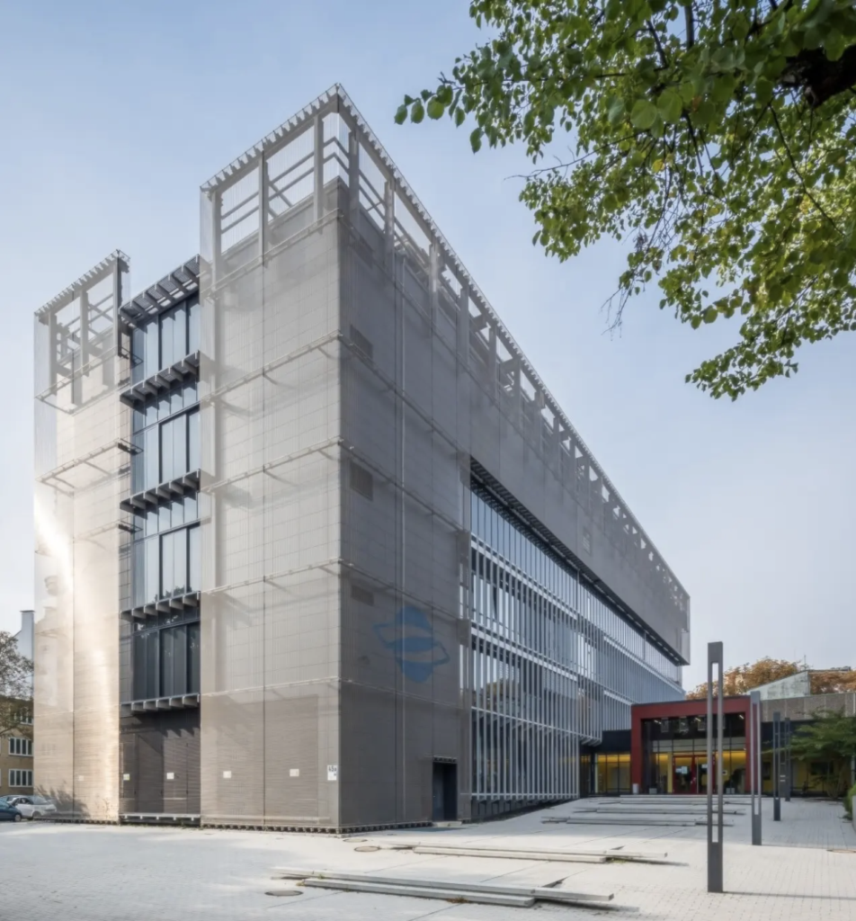 A photo shows a modern-looking, glassy building beside a tree